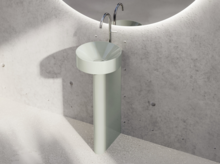 Rundes Stahl-Email Waschbecken mit zylindrischem Standfuß vor Betonwand, moderner Wasserhahn, kein Waschtisch Einbauplatte.